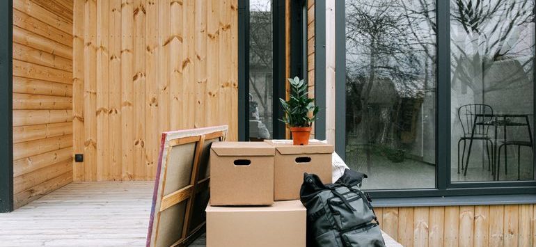 Cardboard moving boxes stacked on a covered wooden porch